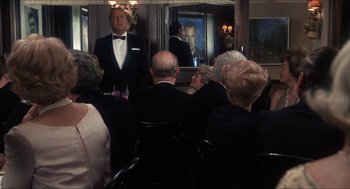 Movie still from “Shampoo” (1975), directed by Hal Ashby – A group of people sitting in front of a mirror in a room; Medium shot, Over the shoulder angle