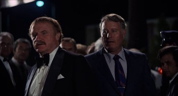 Movie still from “Shampoo” (1975), directed by Hal Ashby – A couple of men standing next to each other in suits; Medium shot, Low angle