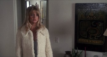 Movie still from “Shampoo” (1975), directed by Hal Ashby – A woman standing in front of a mirror in a room; Medium shot, Over the shoulder angle