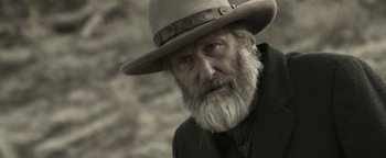 Movie still from “Godless” (2017), directed by Scott Frank – An old man with a long beard wearing a hat; Close Up shot, Over the shoulder angle