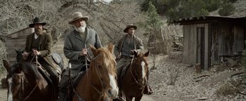 Movie still from “Godless” (2017), directed by Scott Frank – Two men riding horses down a dirt road; Wide shot, Over the shoulder angle