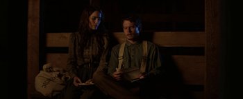 Movie still from “Godless” (2017), directed by Scott Frank – A man and a woman sitting next to each other on a bench; Medium shot, Low angle