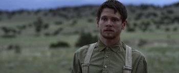 Movie still from “Godless” (2017), directed by Scott Frank – A man in a field wearing suspenders and a button down shirt; Close Up shot, Over the shoulder angle