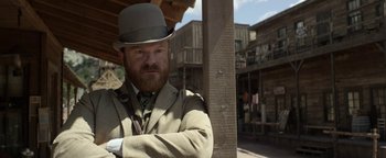 Movie still from “Godless” (2017), directed by Scott Frank – A man with a beard wearing a suit and a hat; Medium shot, Low angle