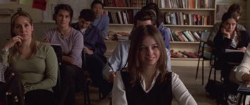 Movie still from “Shattered Glass” (2003), directed by Billy Ray – A woman sitting in front of a group of people in a room; Medium shot, Over the shoulder angle