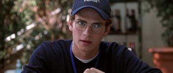 Movie still from “Shattered Glass” (2003), directed by Billy Ray – A young man wearing glasses and a blue hat; Close Up shot, Over the shoulder angle