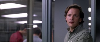 Movie still from “Shattered Glass” (2003), directed by Billy Ray – A man standing in front of a window in an office building; Close Up shot, Over the shoulder angle