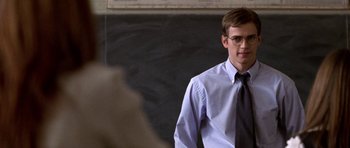 Movie still from “Shattered Glass” (2003), directed by Billy Ray – A man in a tie and glasses standing in front of a chalkboard; Close Up shot, Over the shoulder angle