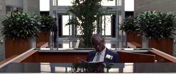 Movie still from “Shattered Glass” (2003), directed by Billy Ray – A man sitting at a table reading a magazine; Medium shot, Over the shoulder angle