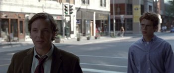 Movie still from “Shattered Glass” (2003), directed by Billy Ray – A man standing on a city street in front of a building; Close Up shot, Over the shoulder angle