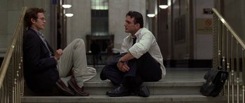 Movie still from “Shattered Glass” (2003), directed by Billy Ray – A man sitting on the steps of a building with his hands on his knees; Medium shot, Low angle