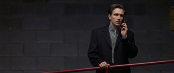 Movie still from “Shattered Glass” (2003), directed by Billy Ray – A man in a suit and tie talking on a cell phone; Medium shot, Low angle