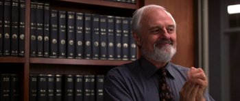 Movie still from “Shattered Glass” (2003), directed by Billy Ray – An older man sitting in front of a book shelf; Close Up shot, Low angle