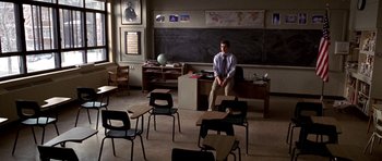 Movie still from “Shattered Glass” (2003), directed by Billy Ray – A man sitting in front of a chalkboard in a classroom; Wide shot, High angle