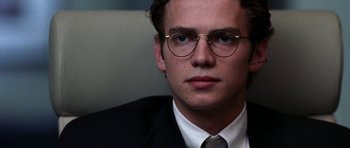 Movie still from “Shattered Glass” (2003), directed by Billy Ray – A man in a suit and tie wearing glasses; Close Up shot, Over the shoulder angle