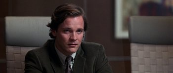 Movie still from “Shattered Glass” (2003), directed by Billy Ray – A man wearing a suit and tie sitting in a room; Close Up shot, Over the shoulder angle