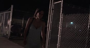 Movie still from “Sherrybaby” (2006), directed by Laurie Collyer – A woman in a white dress standing in front of a fence; Medium shot, Low angle