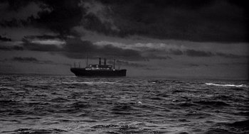 Movie still from “Ship of Fools” (1965), directed by Stanley Kramer – A large boat in the middle of the ocean under a cloudy sky; Extreme Wide shot, Low angle