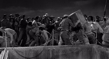Movie still from “Ship of Fools” (1965), directed by Stanley Kramer – A black and white photo of a group of men fighting; Wide shot, High angle