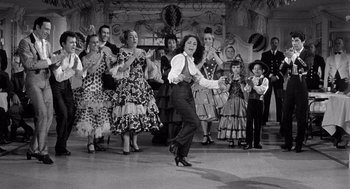 Movie still from “Ship of Fools” (1965), directed by Stanley Kramer – An old photo of a group of people dancing; Wide shot, Low angle