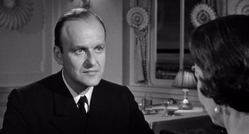 Movie still from “Ship of Fools” (1965), directed by Stanley Kramer – An older man in a suit and tie; Close Up shot, Over the shoulder angle