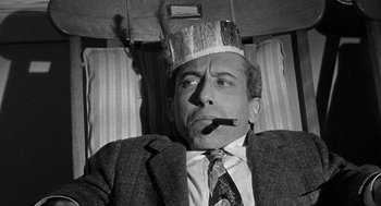 Movie still from “Ship of Fools” (1965), directed by Stanley Kramer – A black and white photo of a man wearing a paper crown; Close Up shot, Overhead angle