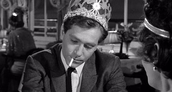 Movie still from “Ship of Fools” (1965), directed by Stanley Kramer – A man wearing a crown and smoking a cigarette; Close Up shot, Over the shoulder angle