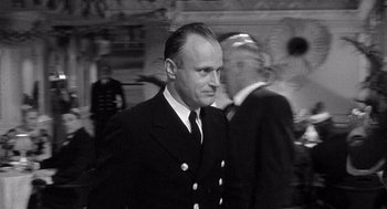 Movie still from “Ship of Fools” (1965), directed by Stanley Kramer – A black and white photo of a man in a suit and tie; Close Up shot, Over the shoulder angle