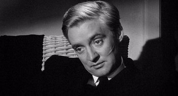 Movie still from “Ship of Fools” (1965), directed by Stanley Kramer – An old black and white photo of a man in a suit and tie; Close Up shot, High angle