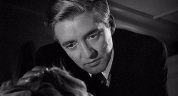 Movie still from “Ship of Fools” (1965), directed by Stanley Kramer – A black and white photo of a man in a suit and tie; Close Up shot, Over the shoulder angle