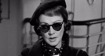 Movie still from “Ship of Fools” (1965), directed by Stanley Kramer – An old photo of a woman wearing a hat and sunglasses; Close Up shot, Low angle