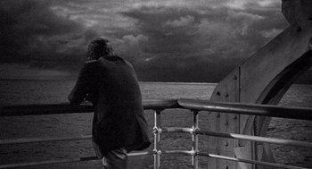 Movie still from “Ship of Fools” (1965), directed by Stanley Kramer – A man looking out over the ocean from a pier; Wide shot, High angle