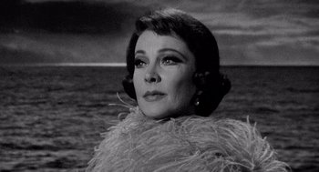 Movie still from “Ship of Fools” (1965), directed by Stanley Kramer – An old photo of a woman in a feather boa; Close Up shot, Low angle