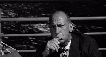 Movie still from “Ship of Fools” (1965), directed by Stanley Kramer – Black and white photograph of a man in a suit and tie looking pensive; Close Up shot, Low angle