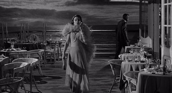 Movie still from “Ship of Fools” (1965), directed by Stanley Kramer – A black and white photo of a woman in a long dress; Wide shot, Over the shoulder angle
