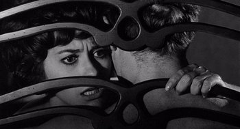 Movie still from “Ship of Fools” (1965), directed by Stanley Kramer – A man and a woman are peeking through some pairs of glasses; Close Up shot, Over the shoulder angle