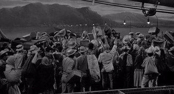 Movie still from “Ship of Fools” (1965), directed by Stanley Kramer – A group of people standing on top of a dock; Wide shot, High angle