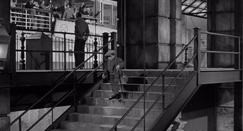 Movie still from “Ship of Fools” (1965), directed by Stanley Kramer – An old man sitting on some steps in front of a building; Wide shot, High angle