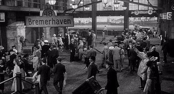 Movie still from “Ship of Fools” (1965), directed by Stanley Kramer – A group of people walking around a train station; Extreme Wide shot, High angle