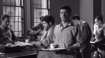 Movie still from “Shock Corridor” (1963), directed by Samuel Fuller – A group of people standing around a table; Medium shot, Low angle