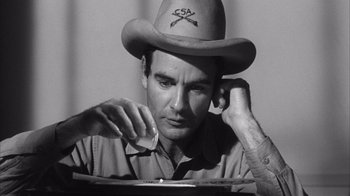 Movie still from “Shock Corridor” (1963), directed by Samuel Fuller – A man wearing a cowboy hat while sitting at a table; Close Up shot, Low angle