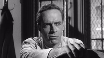 Movie still from “Shock Corridor” (1963), directed by Samuel Fuller – Black and white photograph of a man leaning on a wall; Close Up shot, Low angle