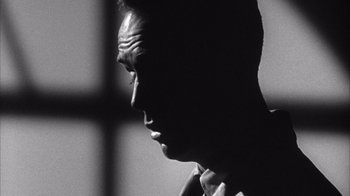 Movie still from “Shock Corridor” (1963), directed by Samuel Fuller – A black - and - white photo of a man's face in front of a window; Close Up shot, Low angle