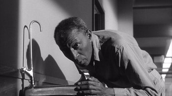 Movie still from “Shock Corridor” (1963), directed by Samuel Fuller – An older man leaning on a metal bar; Close Up shot, High angle