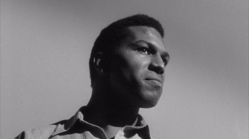 A black and white photo of a man looking up at the sky