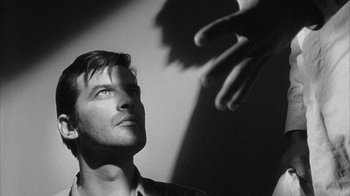 Movie still from “Shock Corridor” (1963), directed by Samuel Fuller – Black and white photograph of a man looking up at a shadow; Close Up shot, Low angle