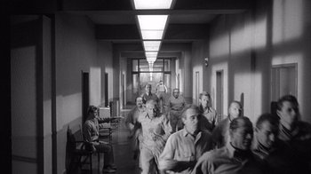 Movie still from “Shock Corridor” (1963), directed by Samuel Fuller – A black and white photo of a group of people in a hallway; Wide shot, High angle