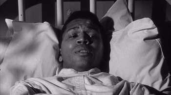 Movie still from “Shock Corridor” (1963), directed by Samuel Fuller – A man laying in a hospital bed with his eyes closed; Close Up shot, Overhead angle
