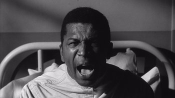 Movie still from “Shock Corridor” (1963), directed by Samuel Fuller – A black and white photo of a man with his mouth wide open; Close Up shot, Low angle