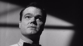 Movie still from “Shock Corridor” (1963), directed by Samuel Fuller – Black and white photograph of a man in a bow tie looking up; Close Up shot, Low angle